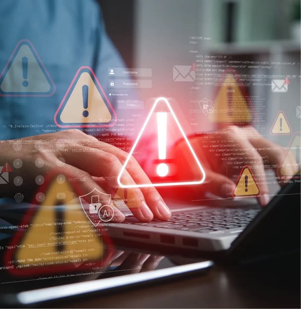Hands typing on a laptop with red warning icons above the keyboard, illustrating threat scenarios in physical risk modeling