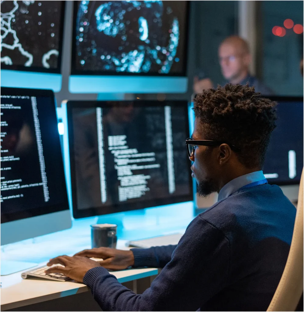 Security operations analyst at multiple monitors in a control room, illustrating executive and operations risk dashboards