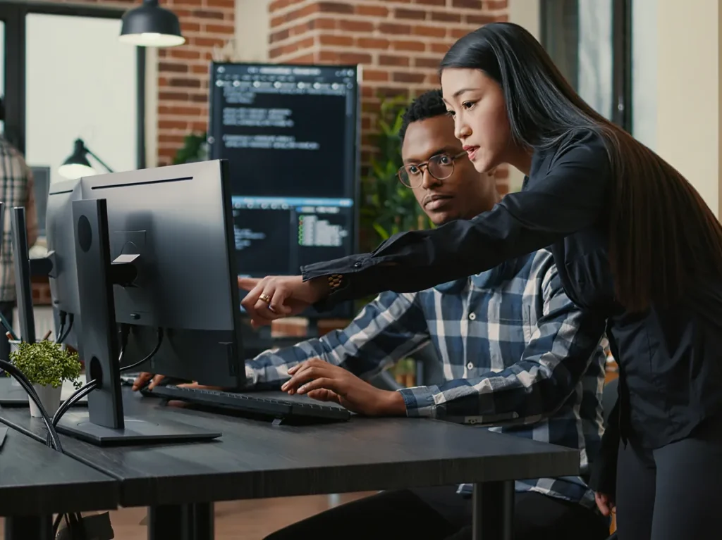 Colleagues gathered at a desk pointing at code on a monitor, illustrating why remediation fails without structure