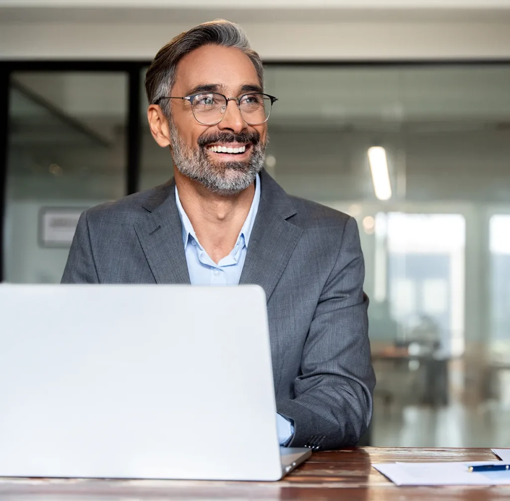 Smiling executive in glasses at a laptop, a chief security officer who knows where they stand at every location