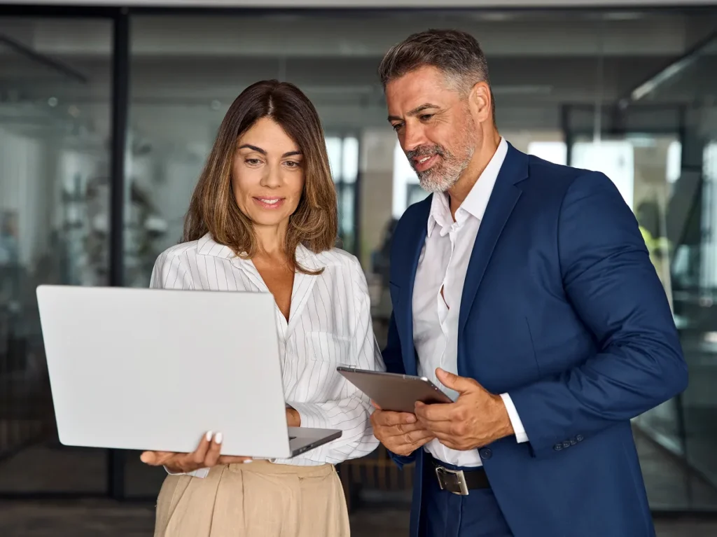 Two executives reviewing a laptop and a tablet, illustrating why one general assessment cannot measure physical risk