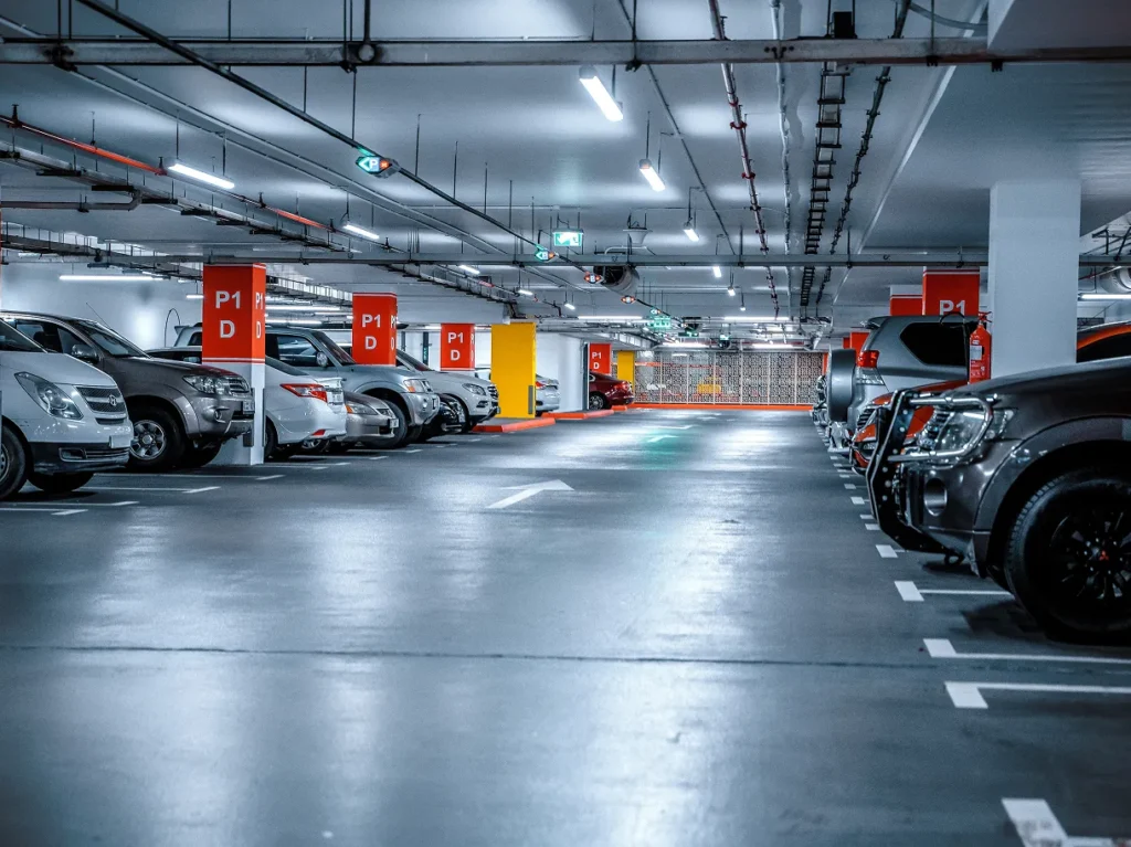 Parking garage with overhead lighting and parked cars, illustrating physical security risk in commercial and residential properties