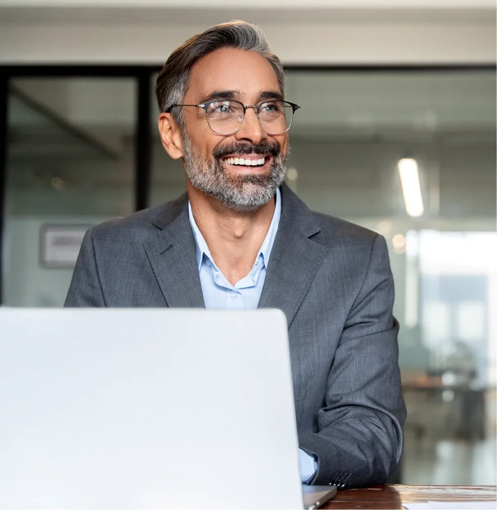 Smiling executive in glasses at a laptop, a leader using Circadian Risk's executive dashboards