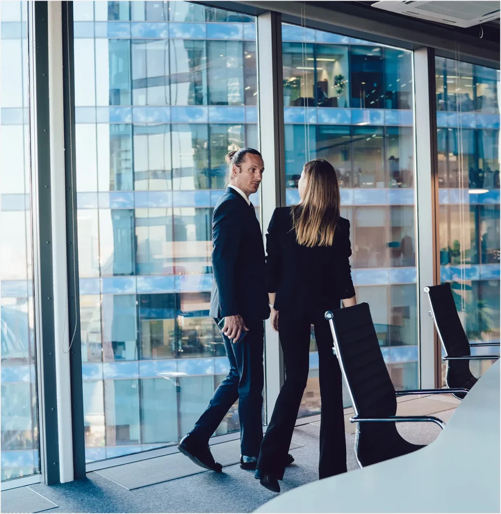 Two executives walking and talking beside a glass-walled office, illustrating a CSO's conversations with leadership