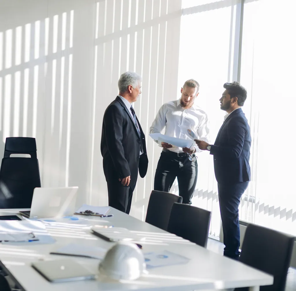 Three professionals shaking hands in a conference room, illustrating faster assessments and stronger deliverables for security consultants