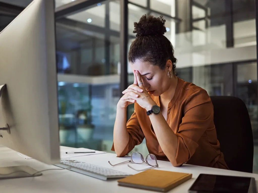 Stressed woman with her hands over her face at a desk, illustrating the pressure on chief security officers accountable for risk at every location