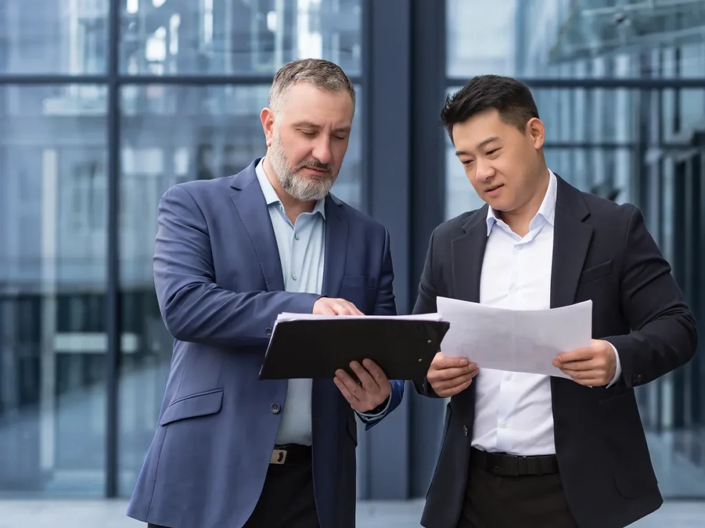 Two colleagues reviewing documents on a tablet and on paper, illustrating physical security risk in acquisition due diligence