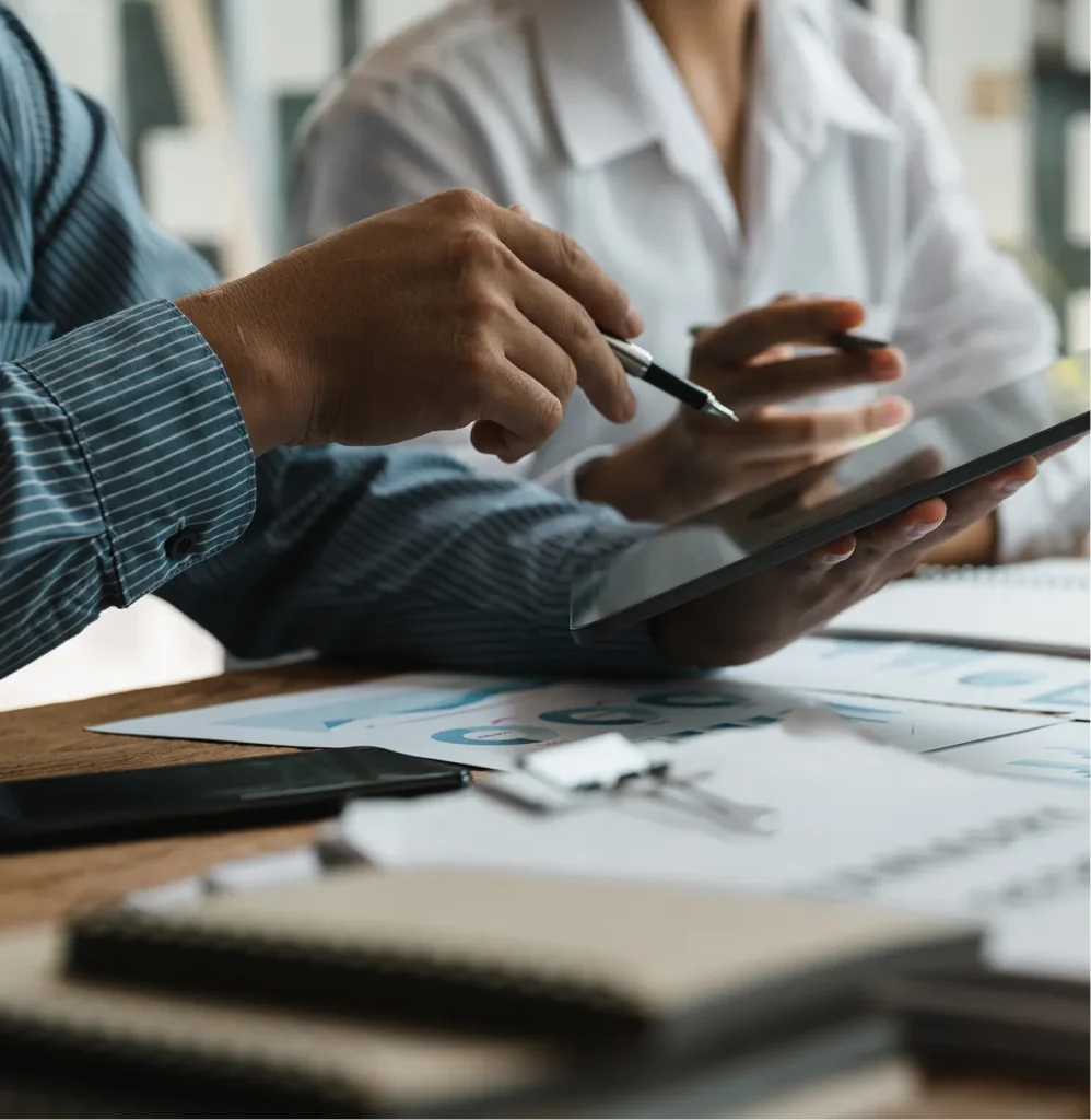 Colleagues reviewing charts on a tablet at a table of reports, illustrating who uses Circadian Risk's executive dashboards